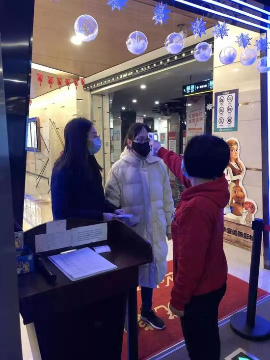 1月23日,通知暂停营业那天,湖北荆州一家华夏国际影城在给员工测量体温(受访者供图)